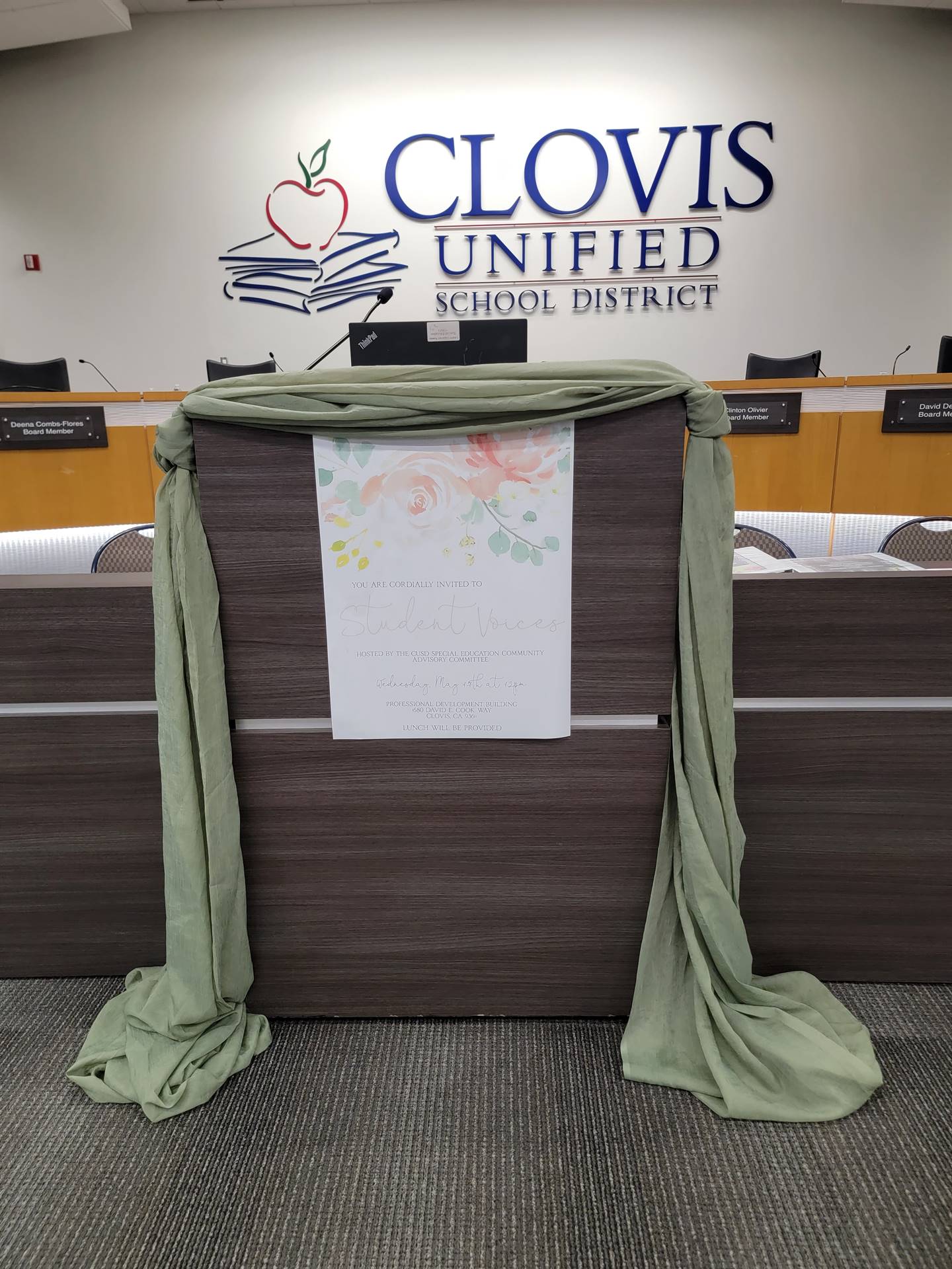board room podium decorated wtih green runner and student voices sign