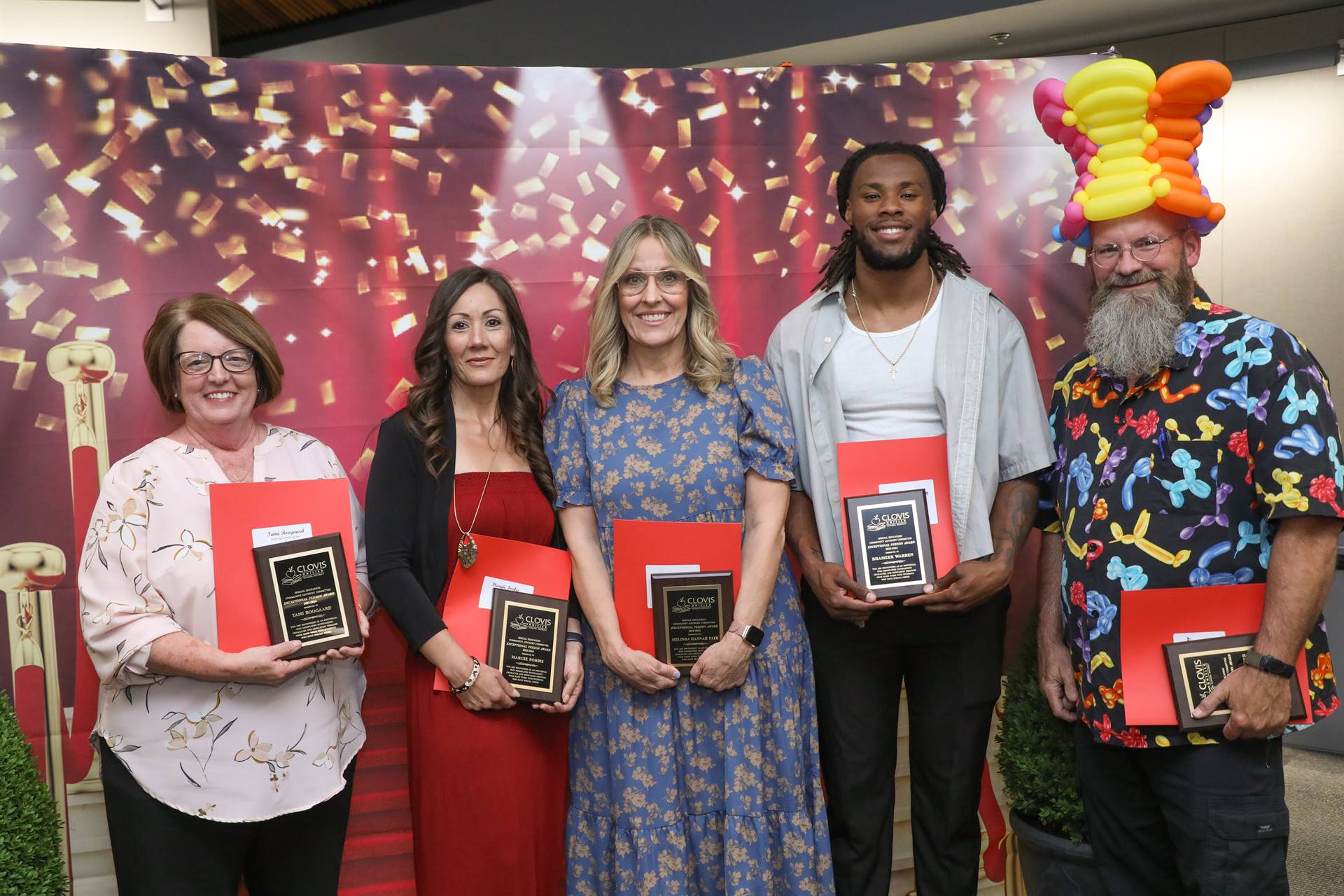 3 Women and 2 men smiling with their awards. One man is wearing a funny balloon hat.