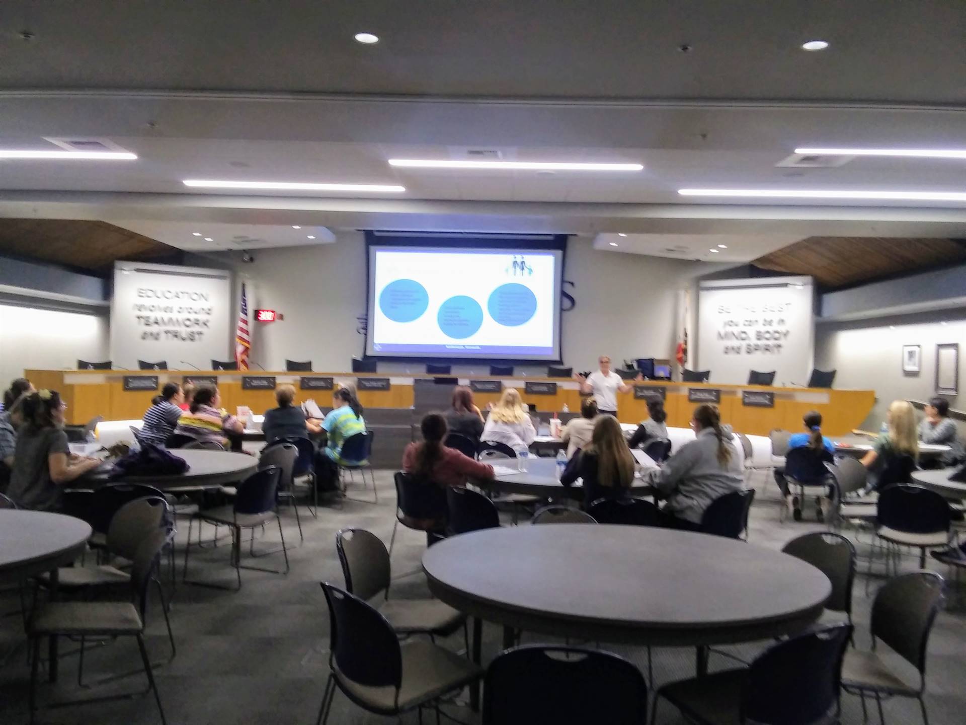 FRC workshop at CUSD boardroom gray round tables, projection screen and many people