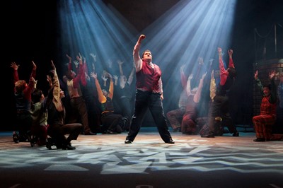 Student in play raising fist in the air, surrounded by other cast members