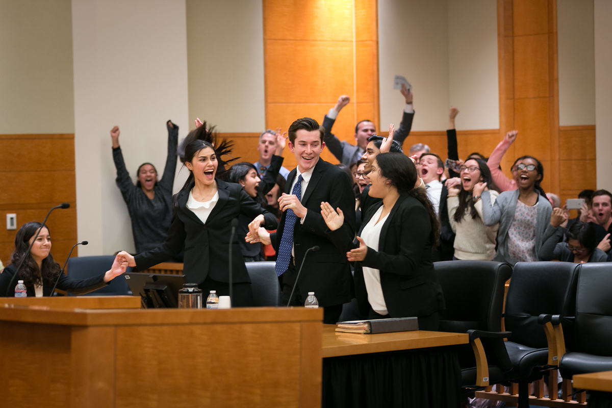 Students in suits celebrating mock trial win